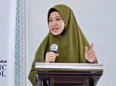 Ustazah Asma Harun menyampaikan ceramah dengan memegang mikrofon di podium