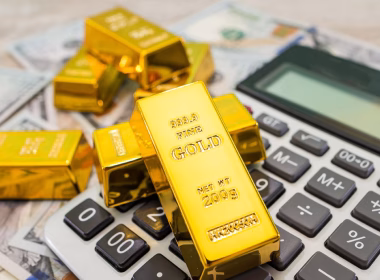 Beberapa jongkong emas 200g di atas mesin kira dan wang kertas dolar Amerika Syarikat