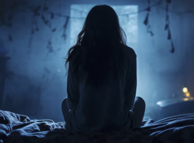 Gambar ilustrasi seorang wanita sedang bercakap seorang diri di dalam rumah gelap, mewakili gangguan makhluk halus yang didakwa dialami oleh Cikgu Nina.
