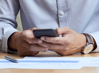 Lelaki memakai kemeja sedang menggunakan telefon di meja kerja pejabat