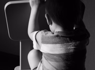 Budak kecil duduk membelakangi kamera dalam suasana gelap, simbolik penderaan atau pengabaian