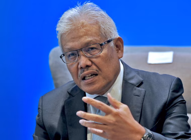 Hamzah Zainudin bercakap semasa sidang media dengan latar belakang biru.