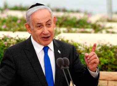 Benjamin Netanyahu berucap di podium dengan latar belakang taman berbunga.