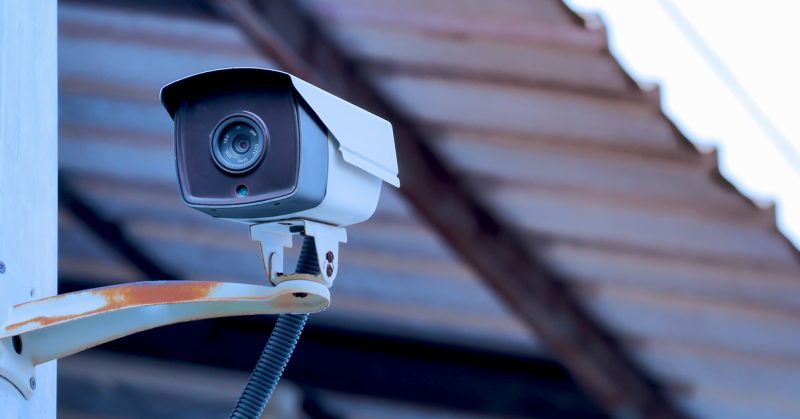 Kamera litar tertutup (CCTV) dipasang di sudut bangunan dengan latar belakang bumbung zink.
