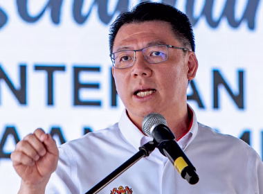 Nga Kor Ming berucap di podium dengan latar belakang paparan teks rasmi.