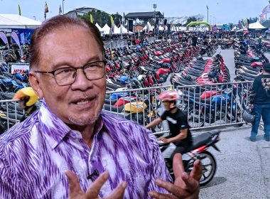 Perdana Menteri Anwar Ibrahim bersama latar belakang acara RXZ Members 7.0 yang dipenuhi deretan motosikal dan pengunjung.