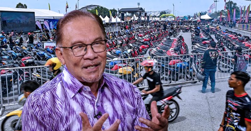 Perdana Menteri Anwar Ibrahim bersama latar belakang acara RXZ Members 7.0 yang dipenuhi deretan motosikal dan pengunjung.