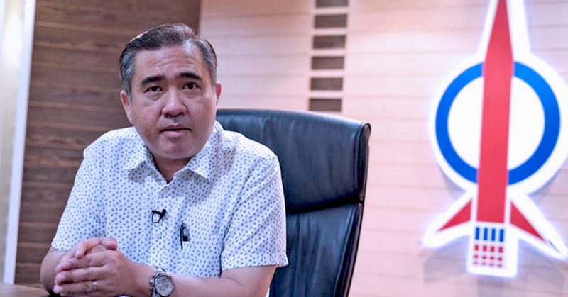 Anthony Loke duduk di meja pejabat dengan logo roket DAP di belakangnya.