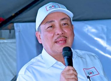 Hajiji Noor berucap dengan memakai topi dan baju GRS, pegang mikrofon ketika majlis.