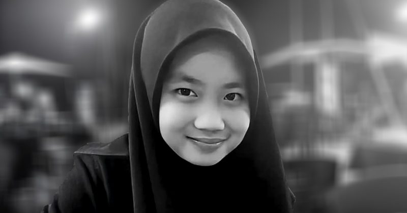 Potret hitam putih remaja perempuan berhijab, wajah tersenyum tenang. Fokus isu Zara Qairina dituduh curi dompet RM300.