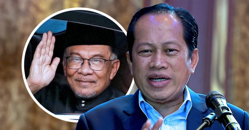 Ahmad Maslan berucap di podium, dengan gambar Anwar Ibrahim melambai di latar bulatan; dikaitkan dengan pengumuman harga petrol RON95 RM1.99.