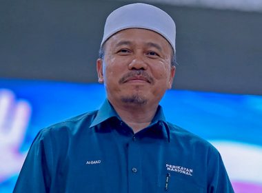 Ahmad Yahaya, Ketua Dewan Ulamak Pas Pusat, memakai baju rasmi Perikatan Nasional sambil tersenyum ketika menghadiri program parti.