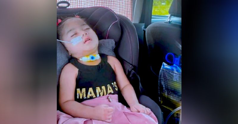 Seorang kanak-kanak perempuan terlantar di kerusi kereta dengan tiub pernafasan dan alat perubatan, mencerminkan derita akibat FIRES Epilepsy.