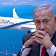 Benjamin Netanyahu berwajah serius duduk bertafakur di hadapan pesawat penumpang yang sedang terbang di atas kawasan perairan.