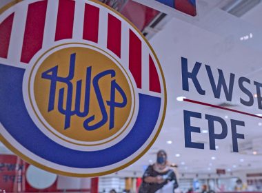Logo KWSP/EPF dipaparkan pada kaca pejabat; kelihatan suasana pejabat dan orang awam di latar belakang.