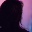 Seorang wanita berdiri membelakangi kamera dalam pencahayaan ungu dan merah jambu, menggambarkan suasana misteri dan identiti yang disembunyikan, berkaitan isu bakal pengantin tular.