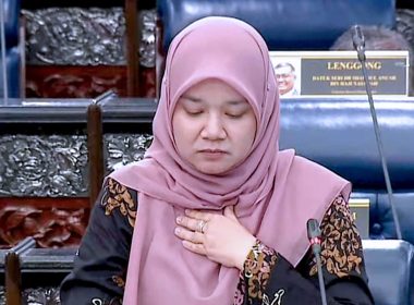 Menteri Pendidikan Fadhlina Sidek menundukkan kepala dengan tangan di dada semasa sesi Parlimen — menggambarkan keprihatinan dan ketegasan beliau dalam isu pelajar disiasat kes gangguan seksual.