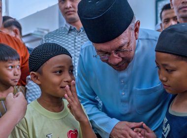 Perdana Menteri Malaysia berinteraksi mesra dengan sekumpulan pelajar lelaki selepas solat Jumaat, menggambarkan nilai kasih sayang dan kepimpinan berteraskan rakyat.
