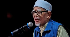 Abdul Hadi Awang berucap di pentas dengan mikrofon, menjelaskan sebab PAS enggan umum calon perdana menteri atas faktor keselamatan.