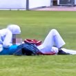Dua individu berpakaian sekolah berada di atas padang awam; seorang duduk menunduk, seorang lagi berbaring sambil beg sekolah diletakkan di sisi.