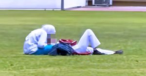 Dua individu berpakaian sekolah berada di atas padang awam; seorang duduk menunduk, seorang lagi berbaring sambil beg sekolah diletakkan di sisi.