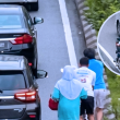 Dua lelaki membantu seorang wanita menolak motosikal rosak di kawasan KL Gateway ketika kesesakan dan hujan renyai