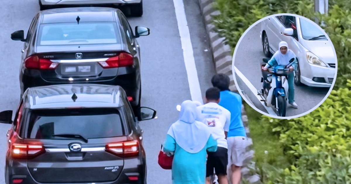 Dua lelaki membantu seorang wanita menolak motosikal rosak di kawasan KL Gateway ketika kesesakan dan hujan renyai