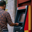 Pelanggan mengeluarkan wang tunai di mesin ATM bank di Malaysia tanpa caj antara bank.