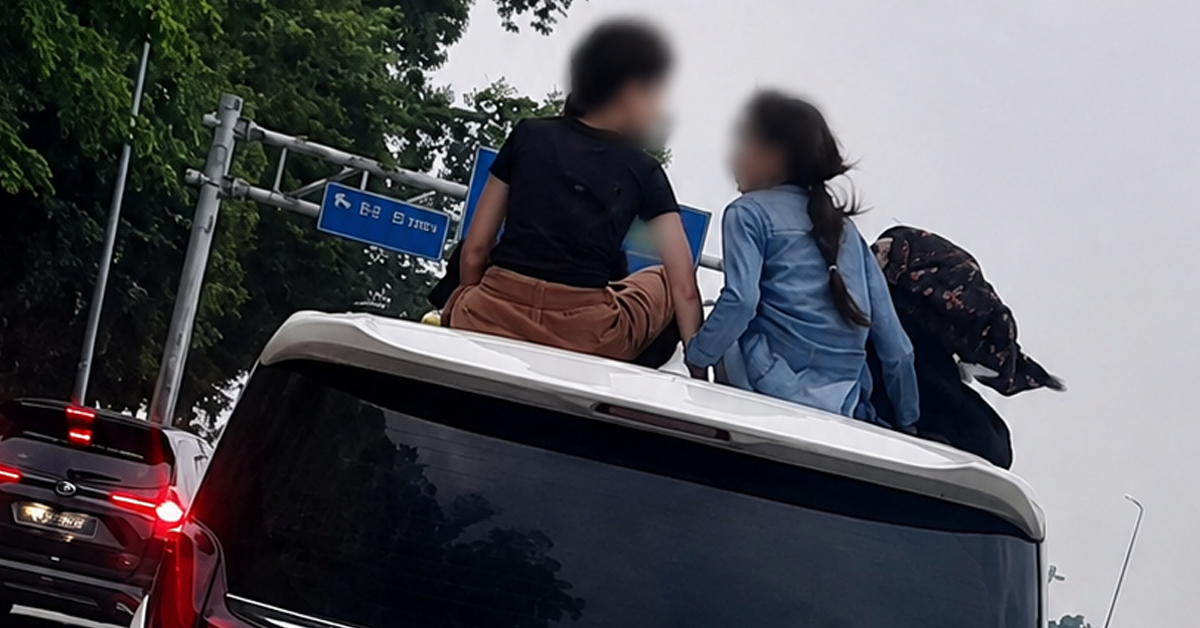 Dua kanak-kanak duduk di atas Toyota Alphard ketika kenderaan sedang bergerak di jalan raya